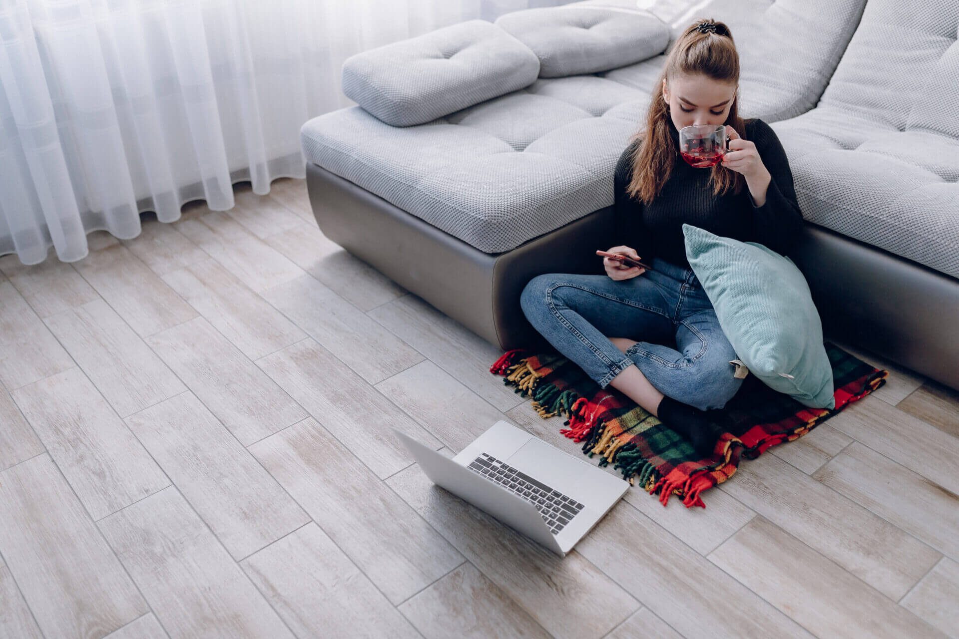 young attractive girl at home working with a laptop and talking on the phone. comfort and coziness while at home. home office and work from home. remote online employment. precio aerotermia piso 80 m2